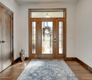 The elegant foyer of a home with a lovely glass front door and sidelights.